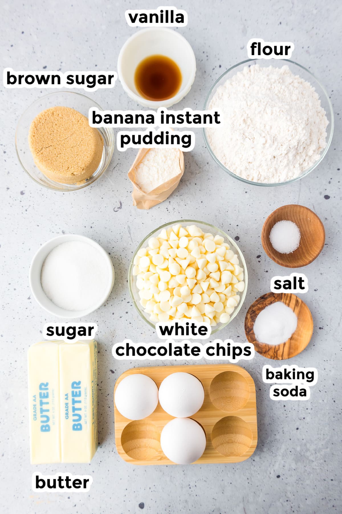 Ingredients for banana pudding cookies in bowls from overhead on a counter with text labels.