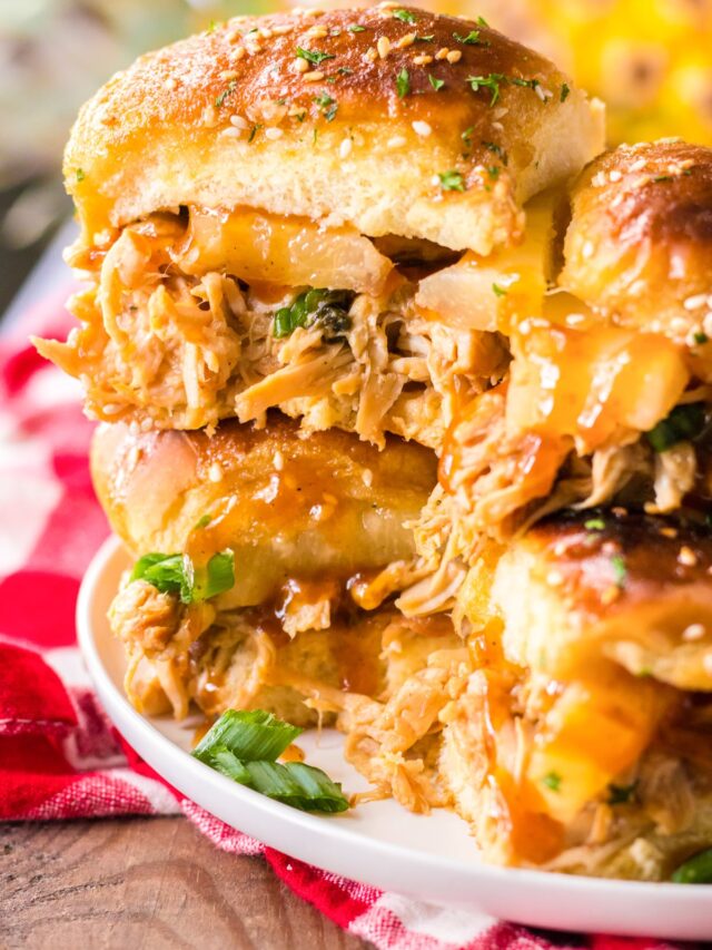 Close up of a bbq hawaiian roll chicken slider on a stack of sliders on a plate from the side.