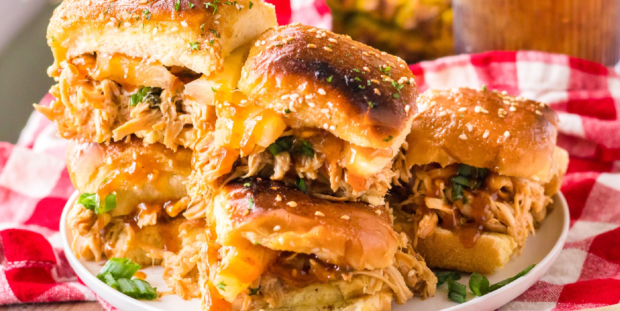 A plate full of bbq Hawaiian roll chicken sliders stacked two high for serving from the side.