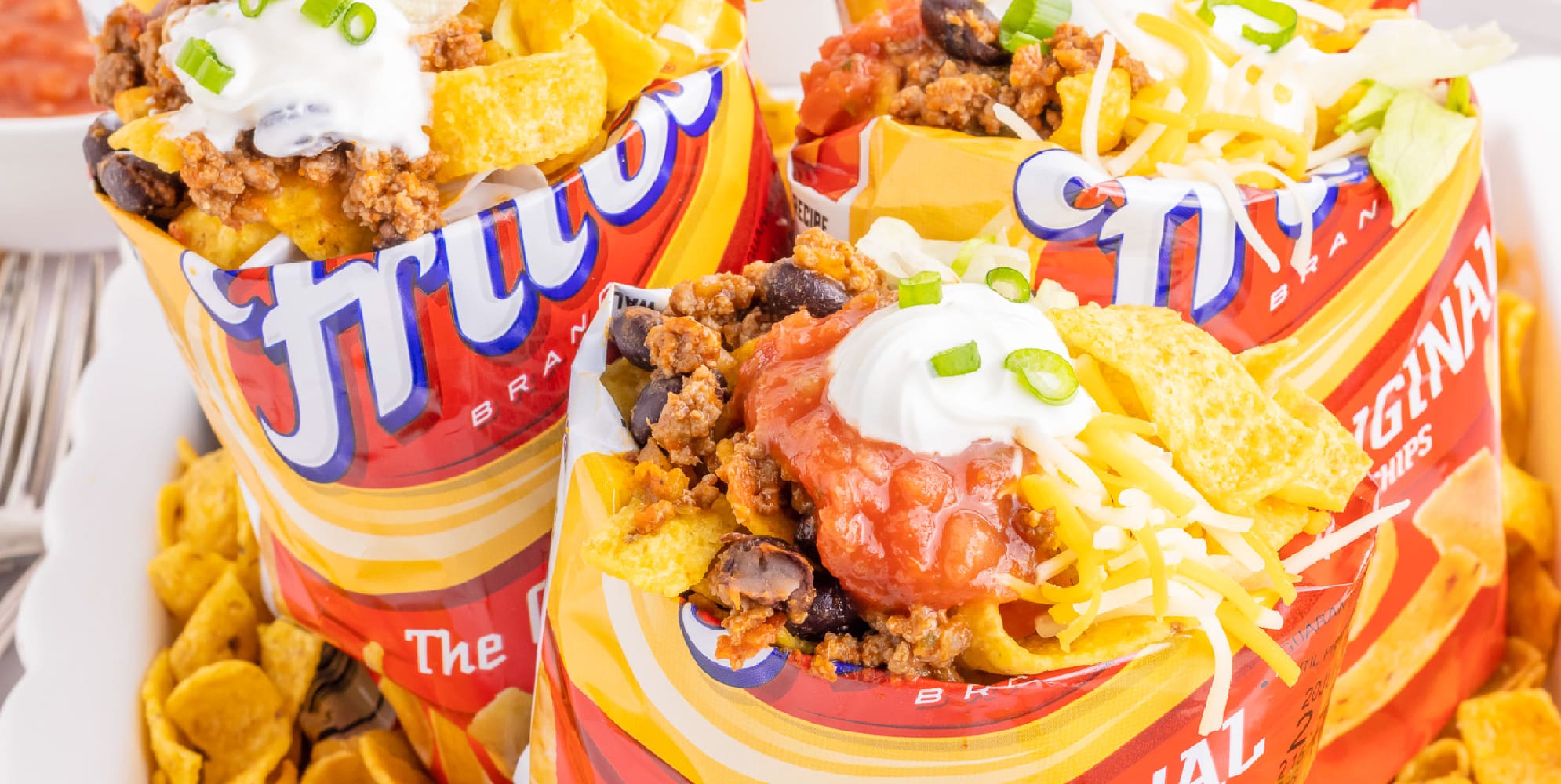 Wide overhead view of three small bags of Fritos corn chips full of taco toppings.
