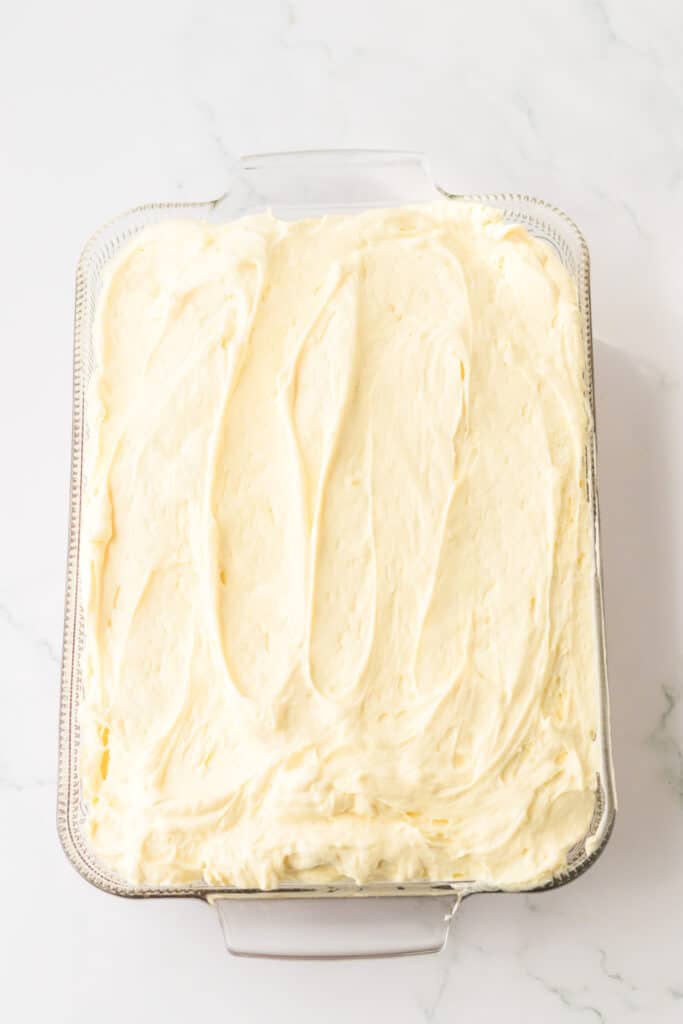 Banana pudding cake in rectangular pan covered in banana flavored custard from overhead.