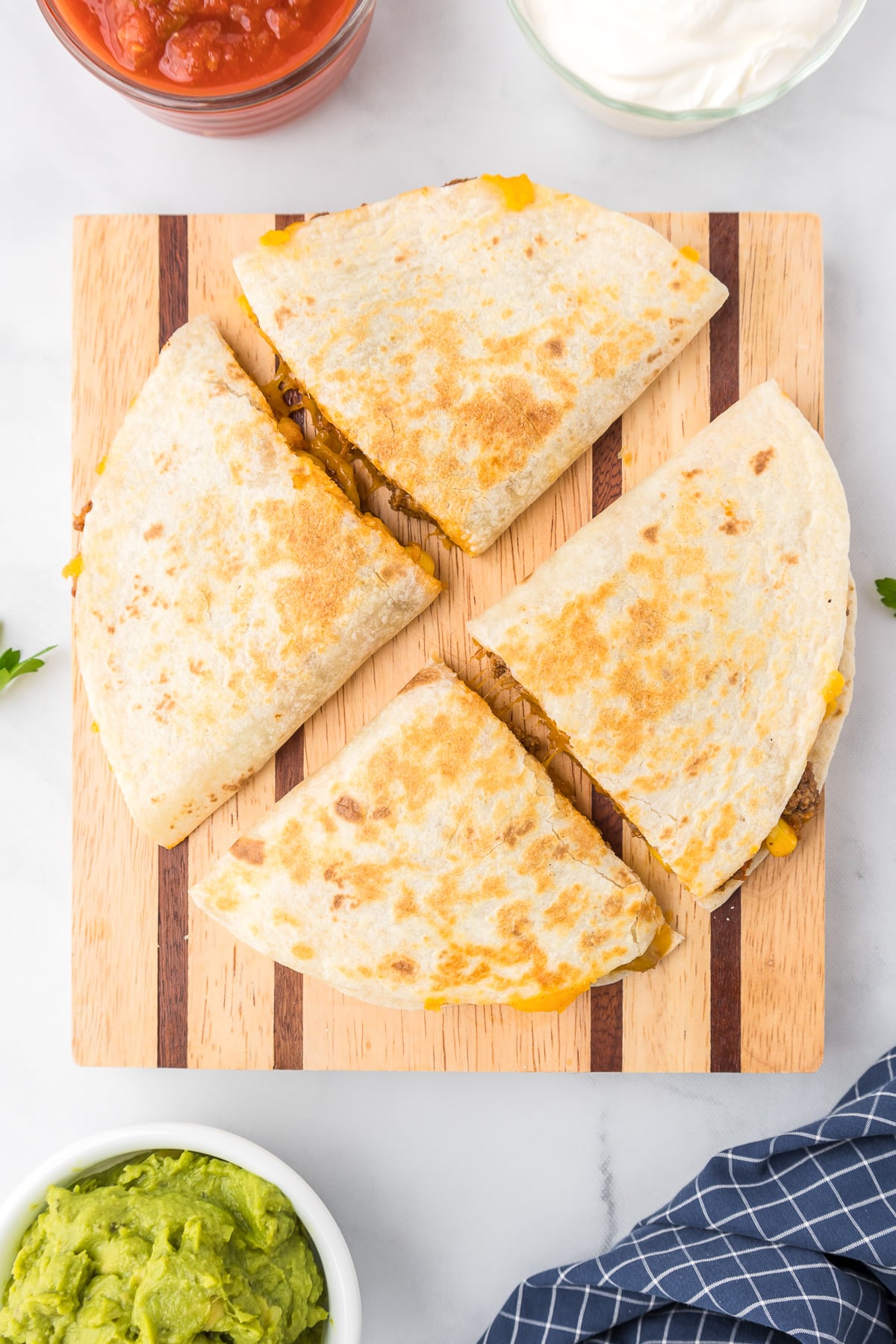 Two half moon shaped quesadillas sliced into triangles on a cutting board from overhead.
