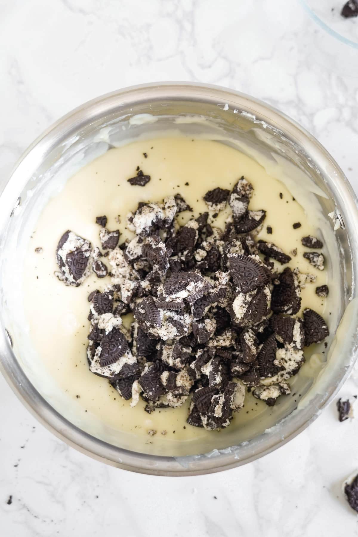 Chocolate cookie crumbs being mixed into the liquid white chocolate fudge mixture.