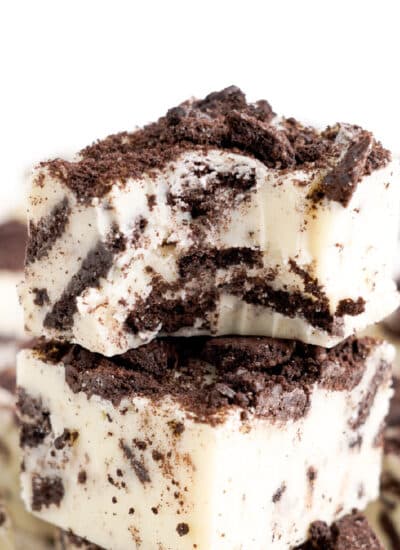 Close up of two pieces of white chocolate fudge mixed with chocolate Oreo cookies close up with the top piece missing a bite.