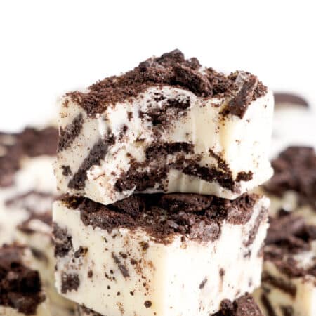 Close up of two pieces of white chocolate fudge mixed with chocolate Oreo cookies close up with the top piece missing a bite.