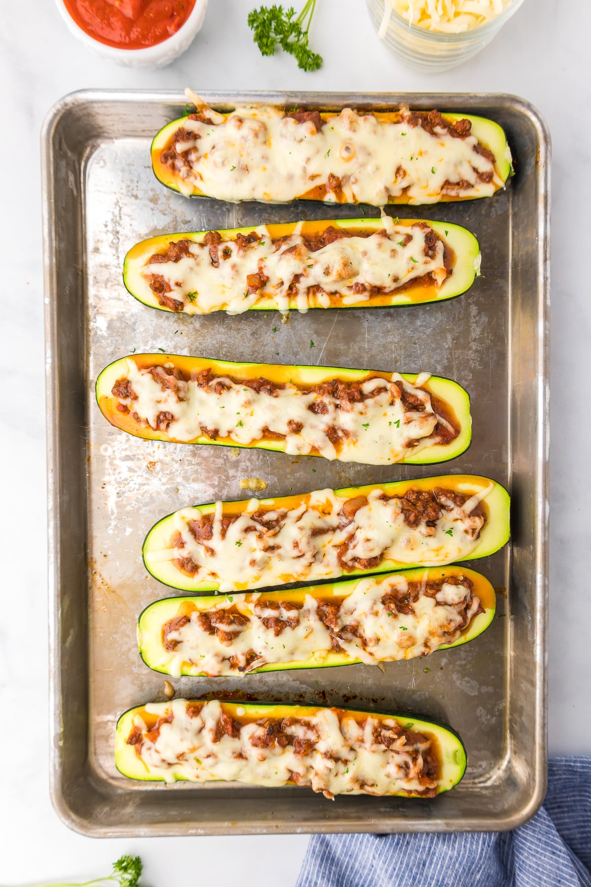 Cooked zucchini on a pan cut lengthwise and stuffed with italian ground beef and cheese from overhead.