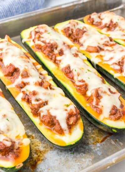 Close up of zucchini boats stuffed with ground beef and cheese on the pan at an angle close up on a pan.