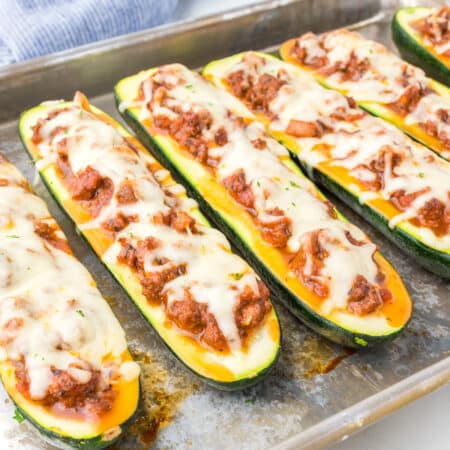 Close up of zucchini boats stuffed with ground beef and cheese on the pan at an angle close up on a pan.
