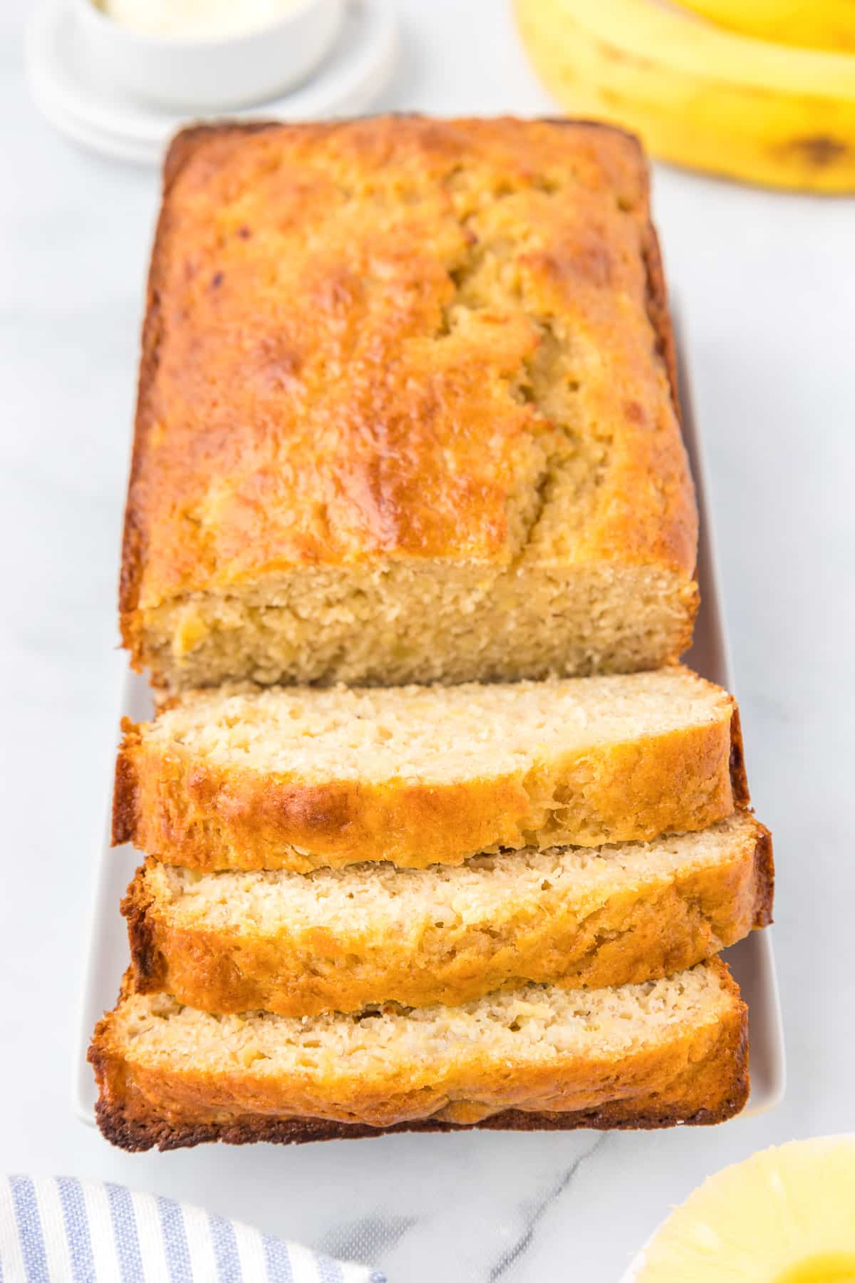 Pineapple banana bread from overhead with three thick sliced on the end of the loaf.