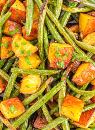 Close up of roasted potatoes and green beans from above on a sheet pan.