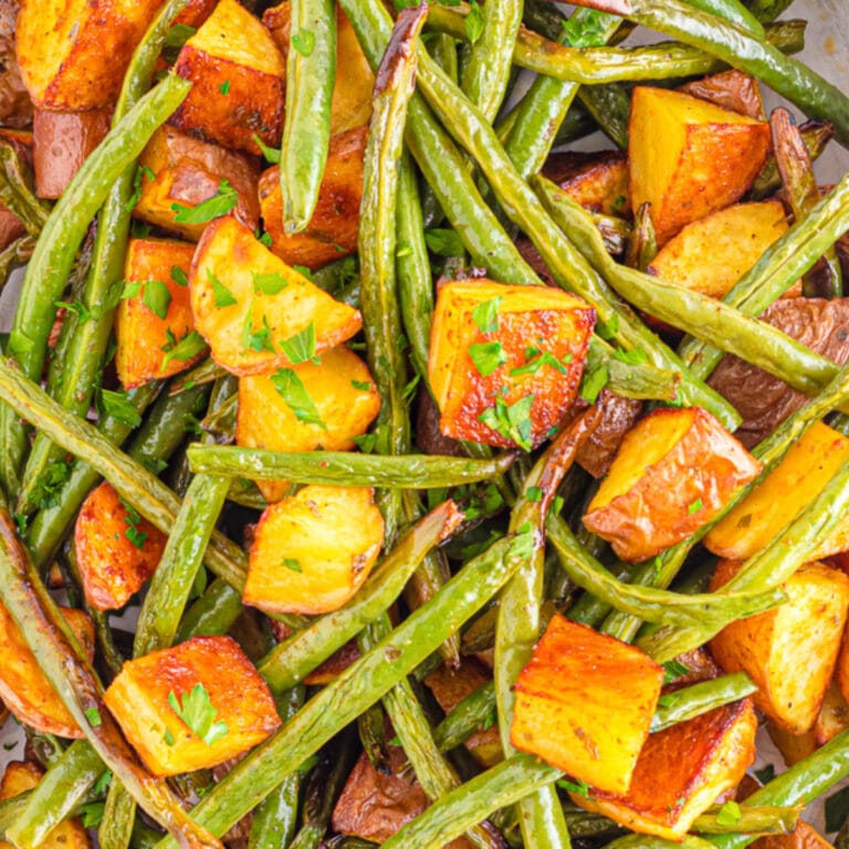 Close up of roasted potatoes and green beans from above on a sheet pan.