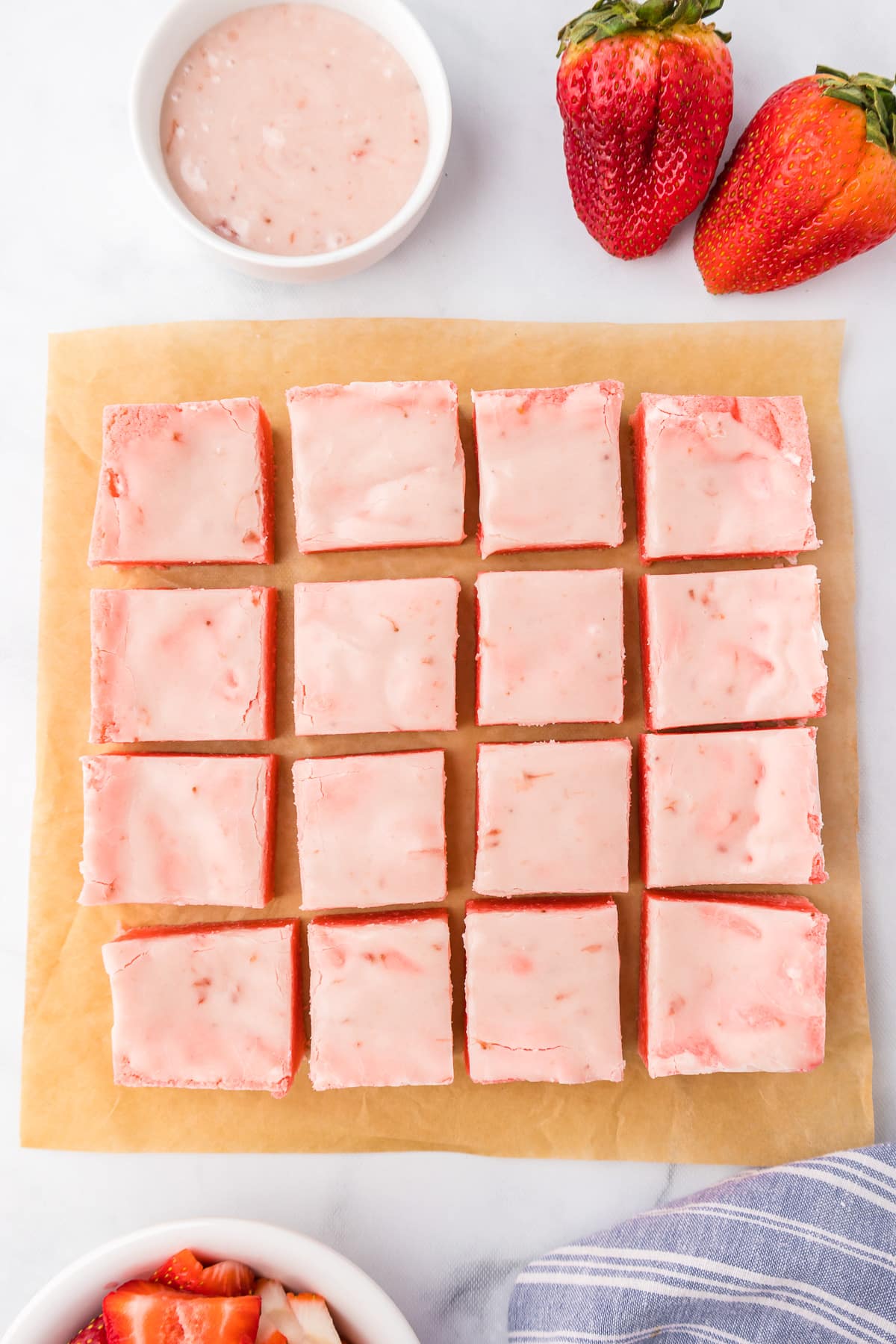 Glazed strawberry brownies in a large square from overhead sliced into sixteen pieces from above on a counter.