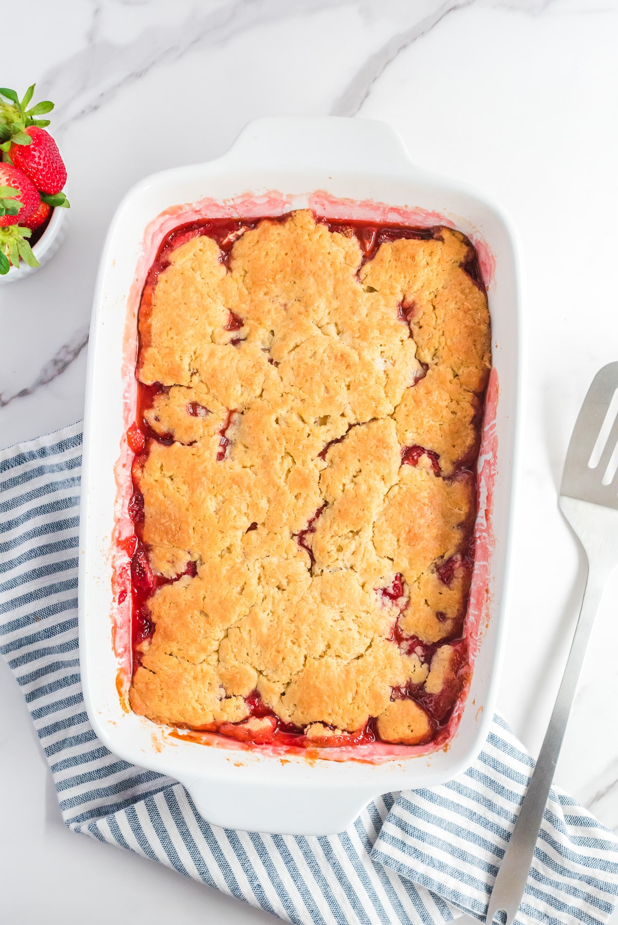 Baked strawberry cobbler in a pan from above on a counter.
