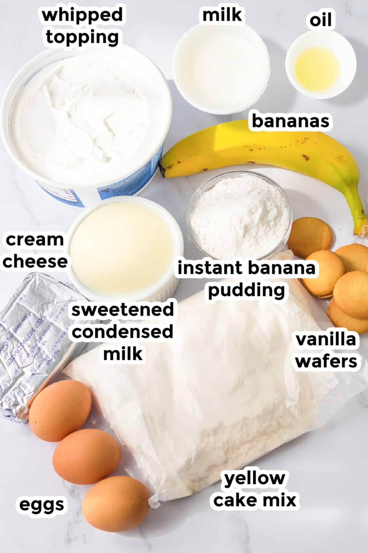 Ingredients for banana pudding poke cake on a counter in bowls with text labels overtop.