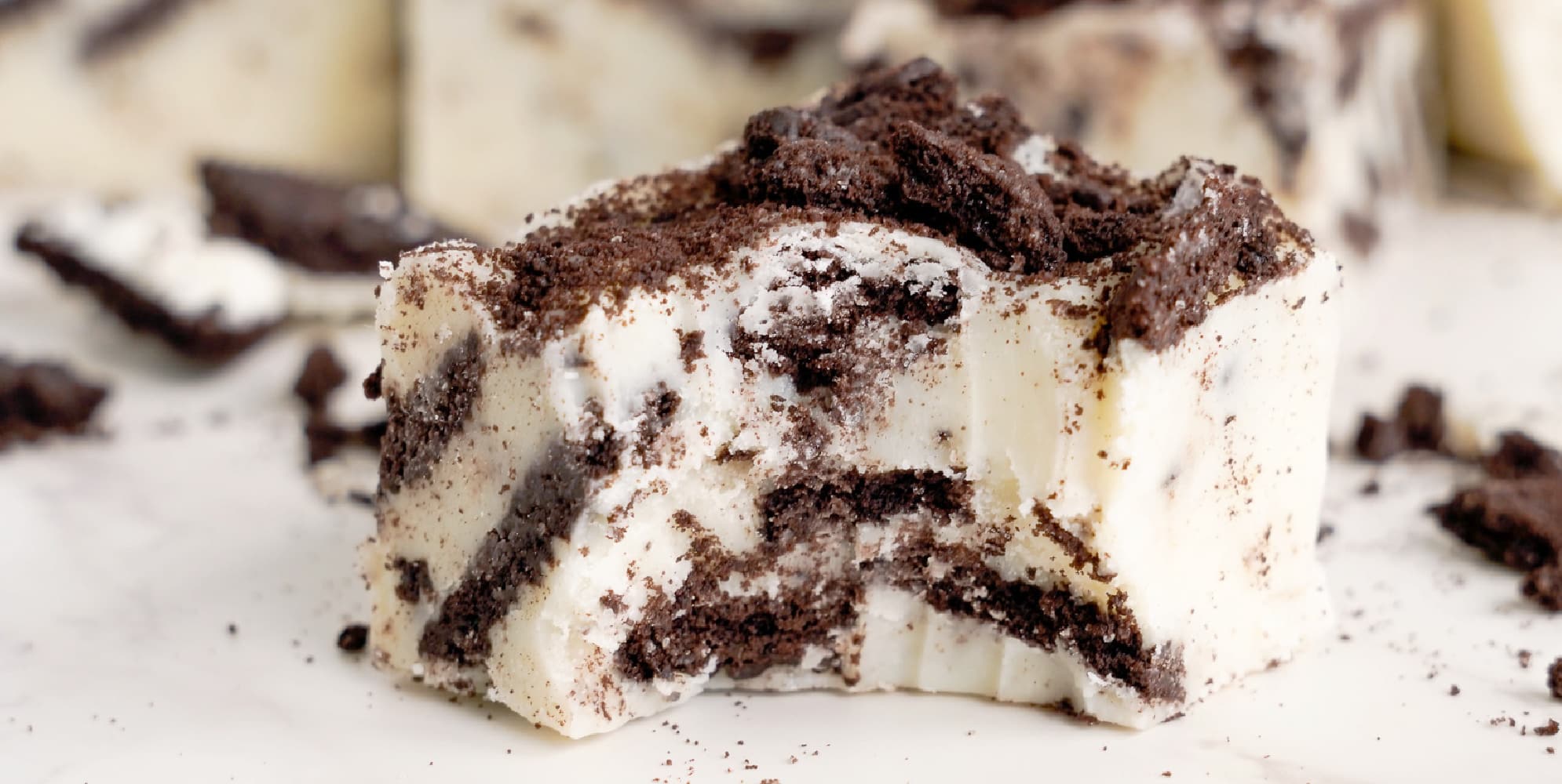 Cookies and cream fudge piece close up bitten showing the chocolate Oreo cookies inside.