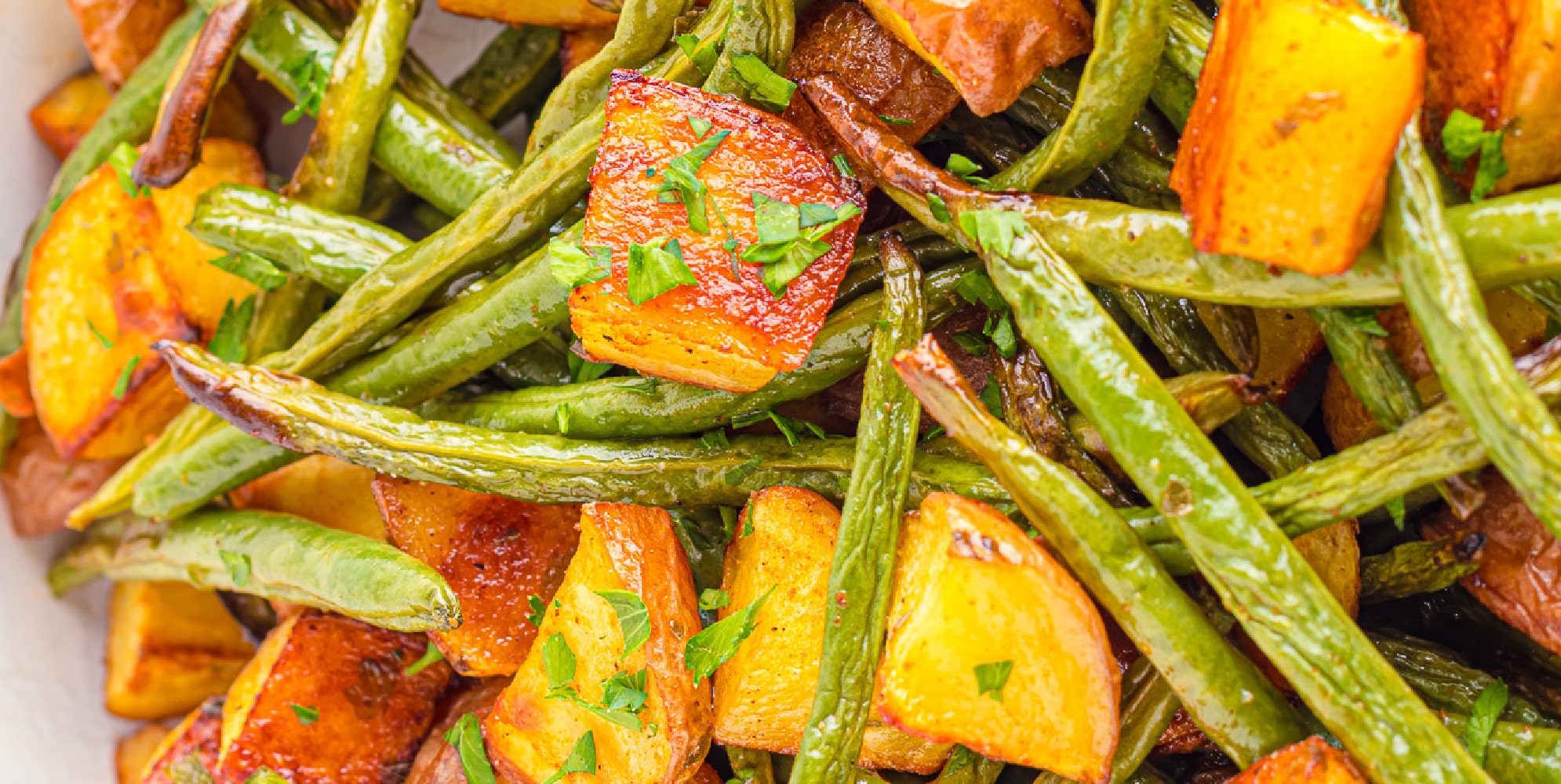 Close up wide view of roasted potatoes and green beans.