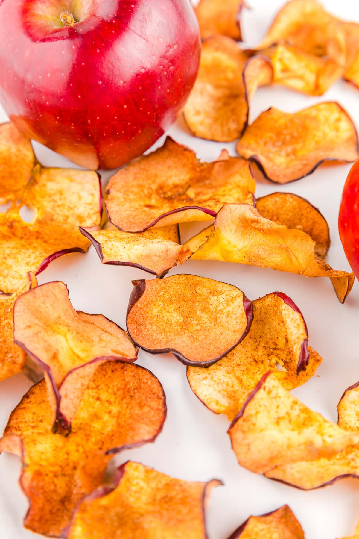 Close up of apple chips next to an apple.