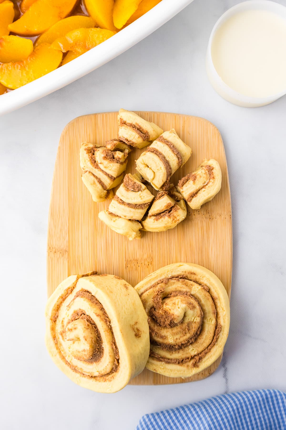 Cinnamon rolls on a cutting board being cut into pieces from overhead.