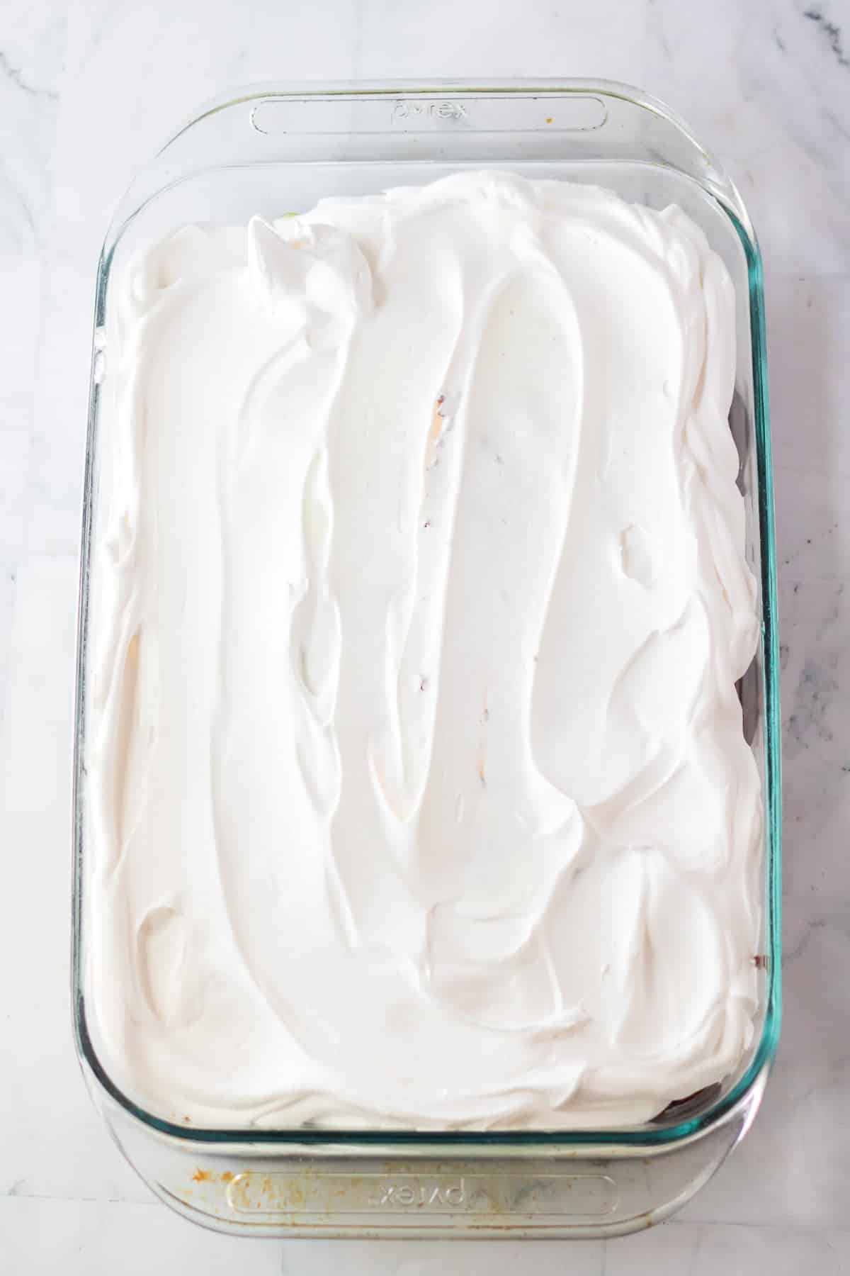 Cake in large rectangular pan topped with white whipped topping.