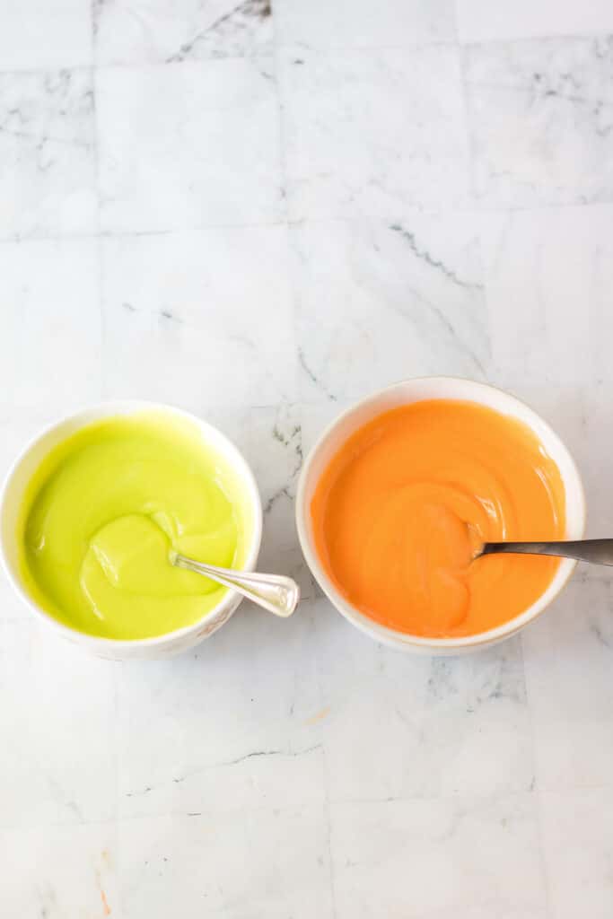 Two bowls full of pudding from above, one green and one orange.