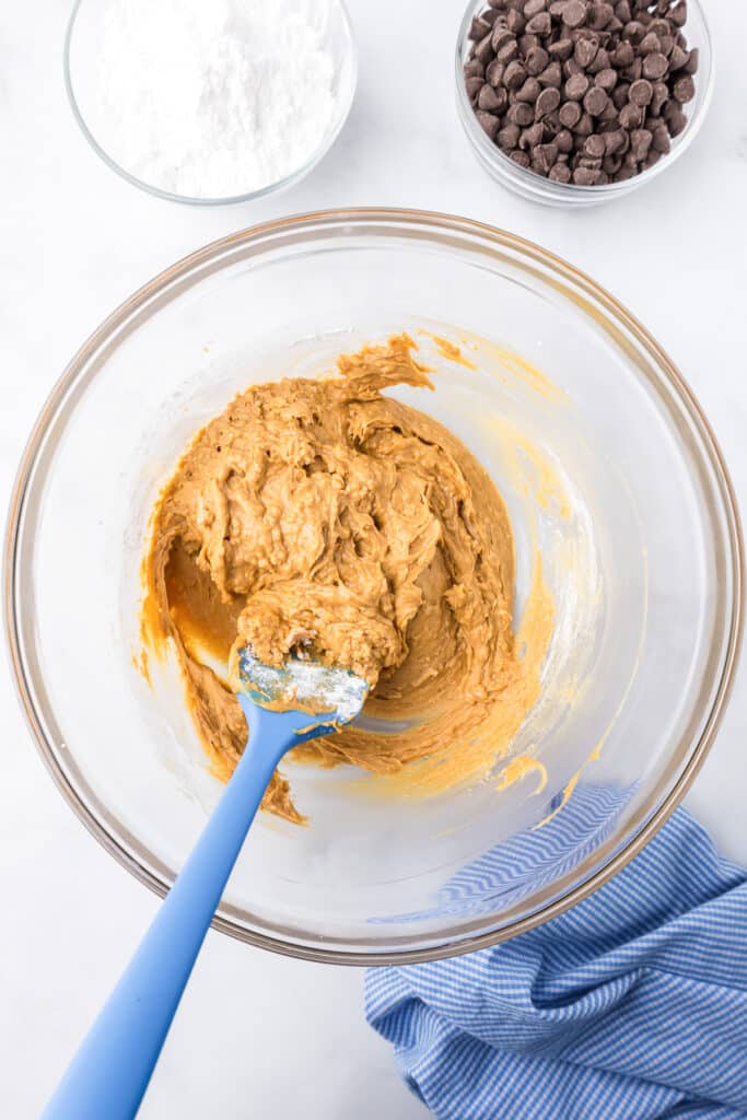 Graham crackers being mixed into the peanut butter mixture in a large bowl from above.