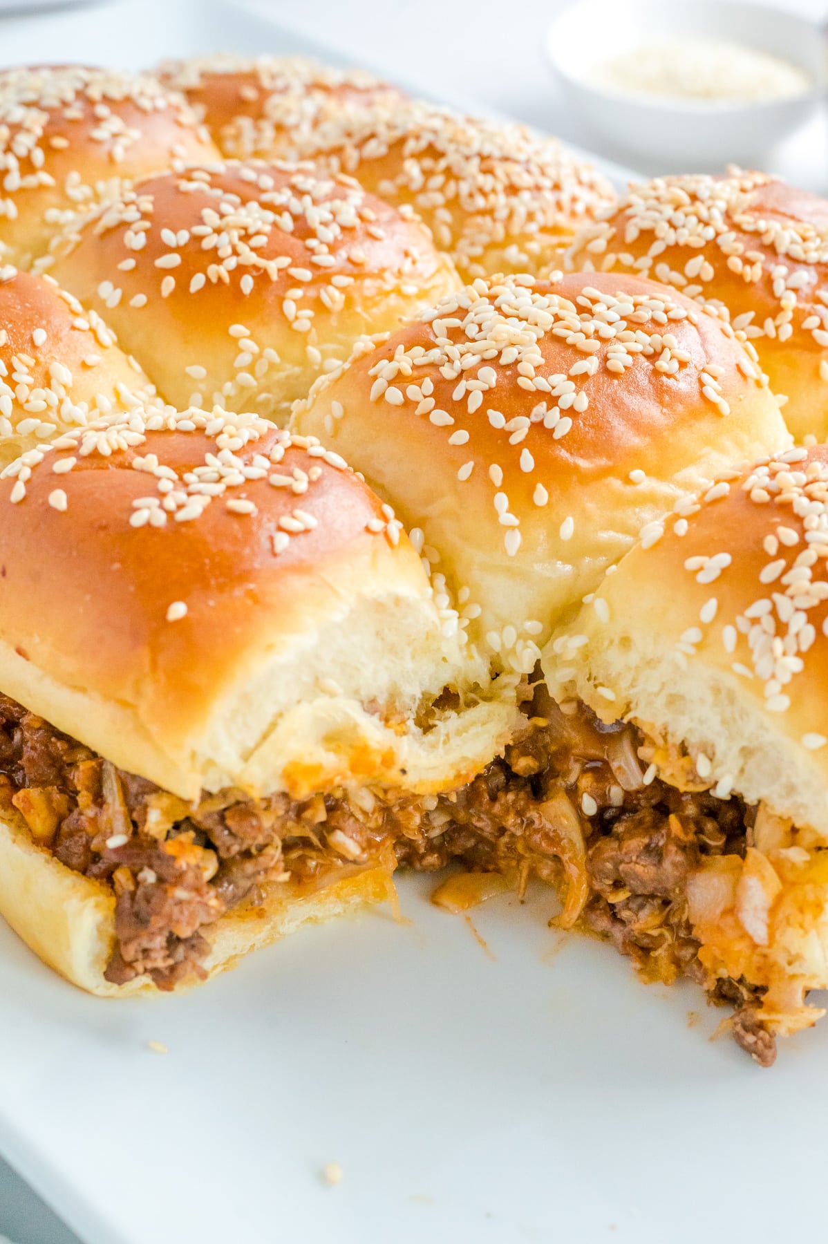 An close up on a plate of sliders with meat and sesame seeds zoomed in on the meaty ground beef filling.