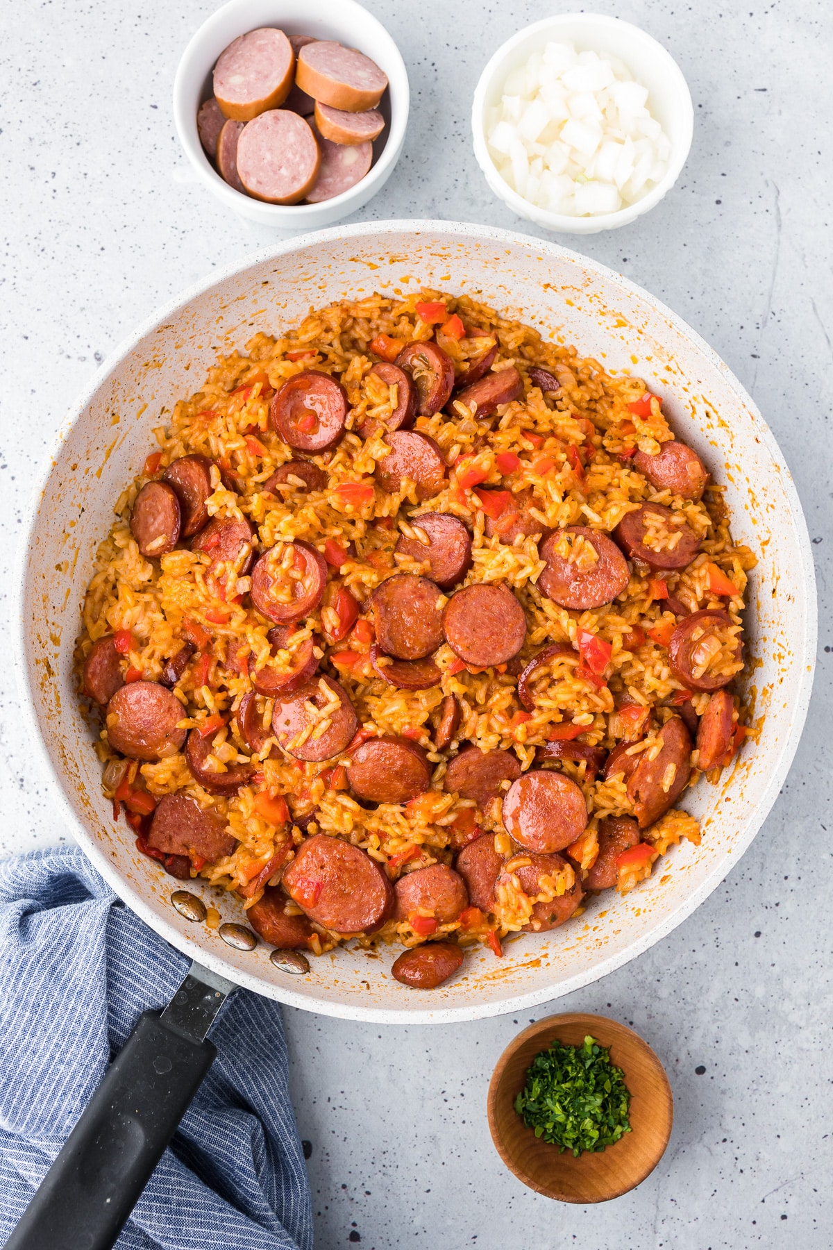 Cooked sausage and red tomato rice in a skillet from above.