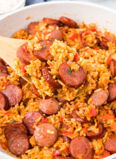 Sausage and rice in a pan with a wooden spoon.