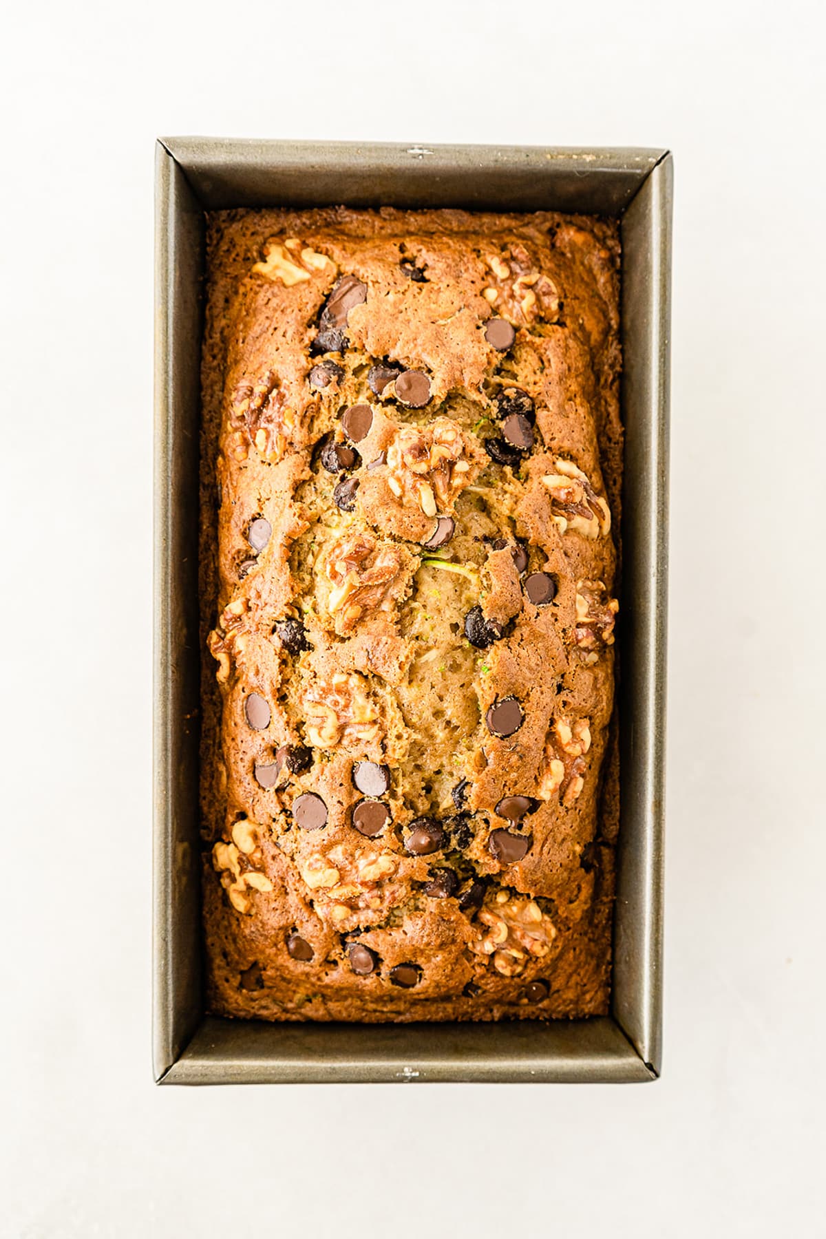 Finished baked chocolate chip walnut zucchini bread load in pan from above on a counter.