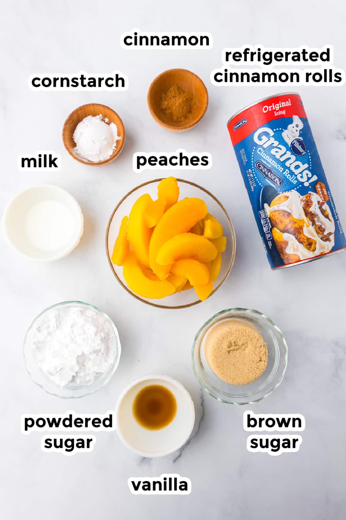 Ingredients for cinnamon roll peach cobbler in bowls from above on a counter with text title labels.