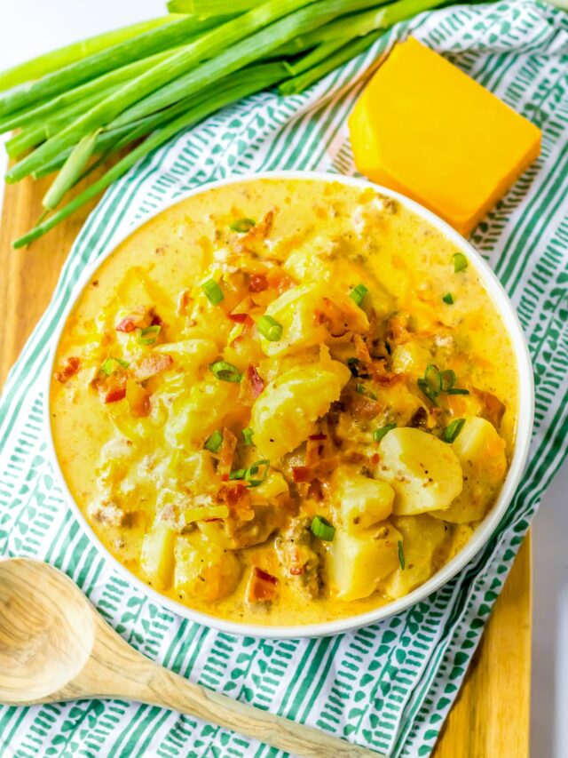 Cheesy cheeseburger potato soup in a bowl on a wooden cutting board.