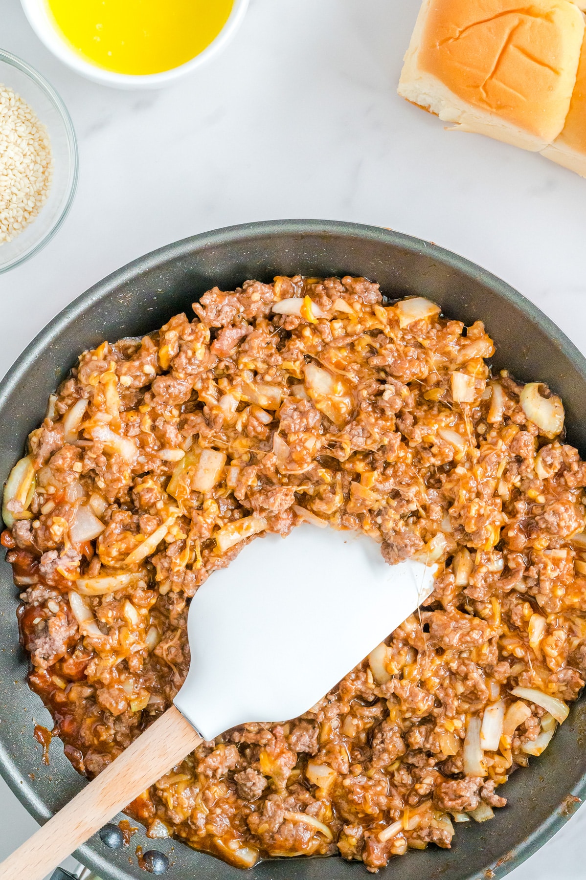 A skillet filled with ground beef, onion and sloppy joe sauce.