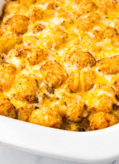 A casserole dish filled with a cheesy tater tot breakfast casserole at an angle.