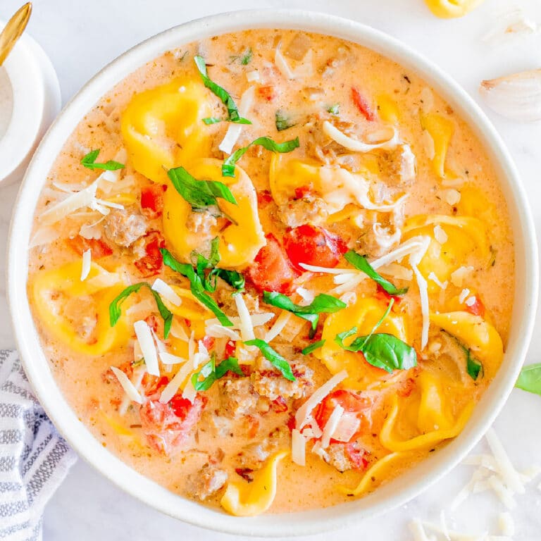 Creamy sausage tortellini soup in a white bowl from above.