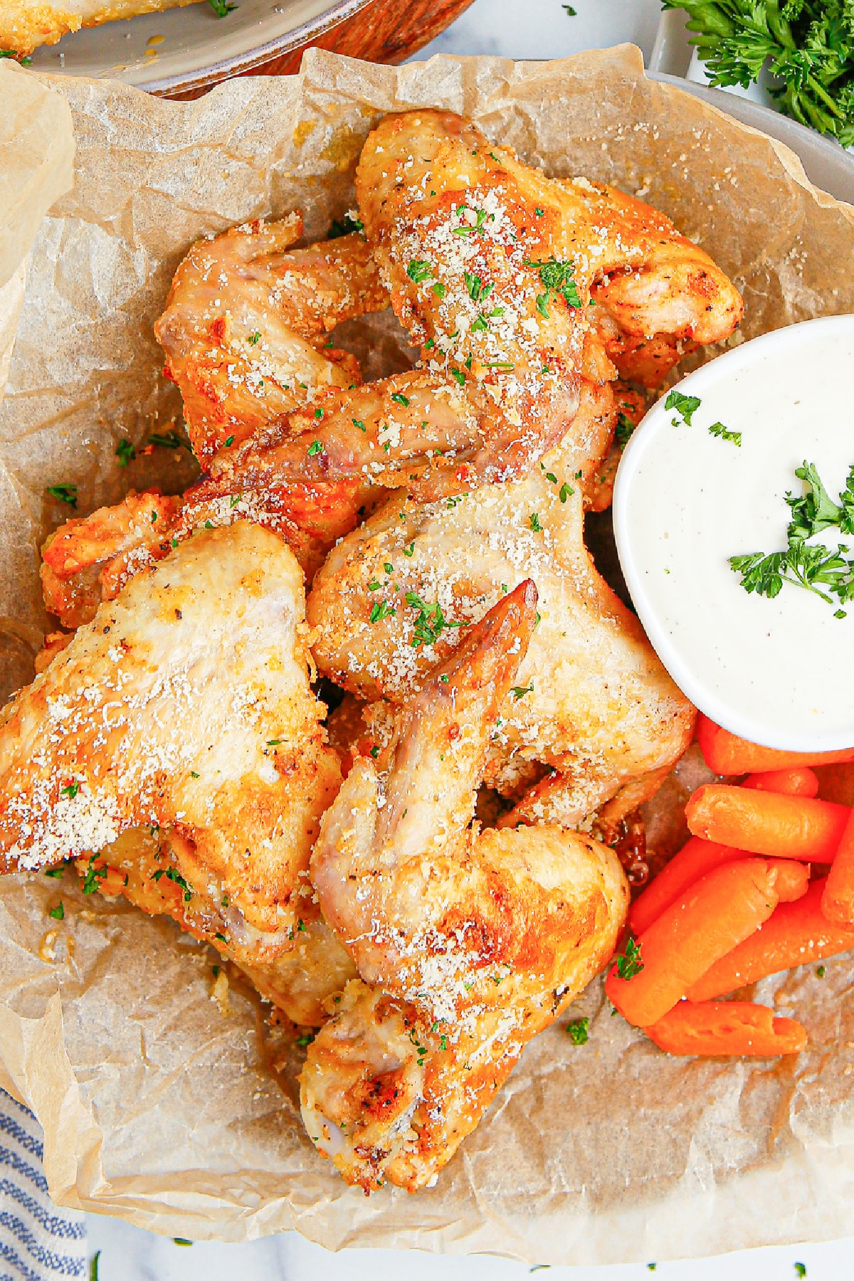 A platter of chicken wings and carrots with a side of dipping sauce.