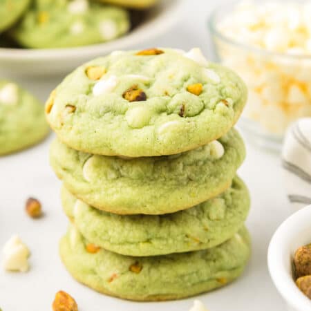 A stack of green pistachio pudding cookies four cookies tall with more cookies in the background.