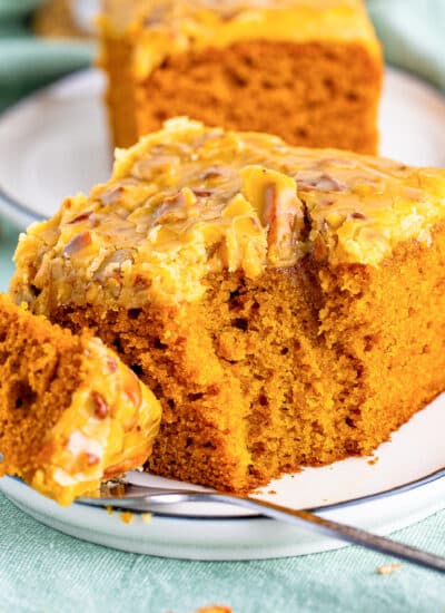 A slice of pumpkin cake on a plate with a fork missing a bite.