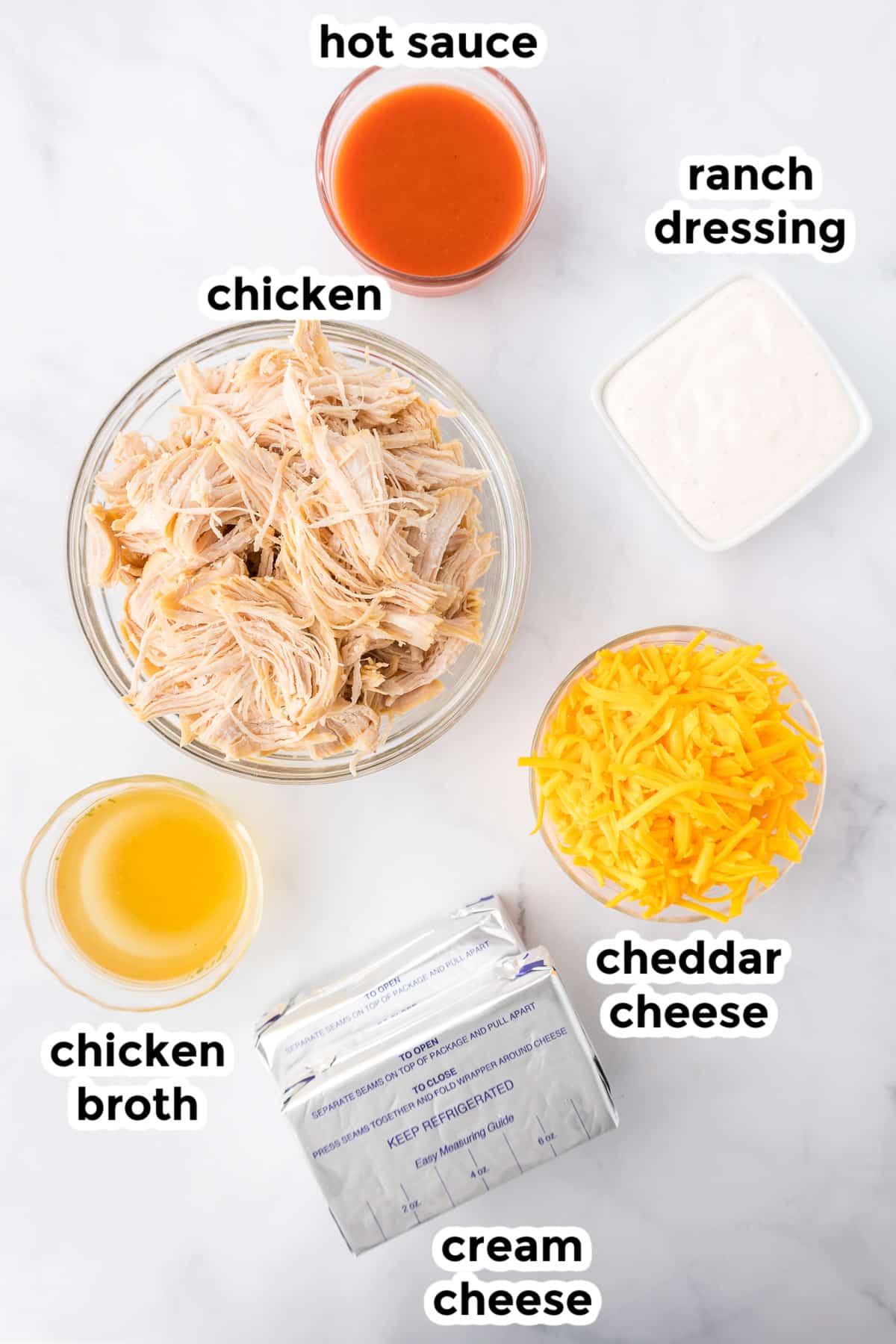 Ingredients for buffalo chicken dip on a counter from overhead with title text labels.