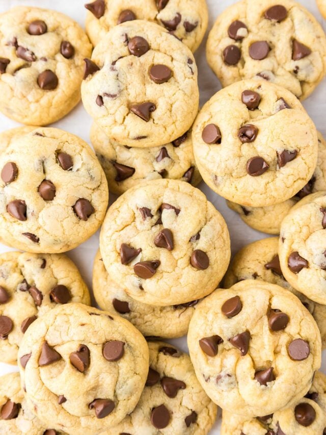 A pile of chocolate chip cookies on a white surface.