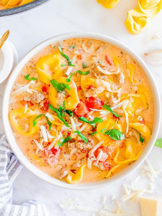 Tortellini soup in a white bowl.