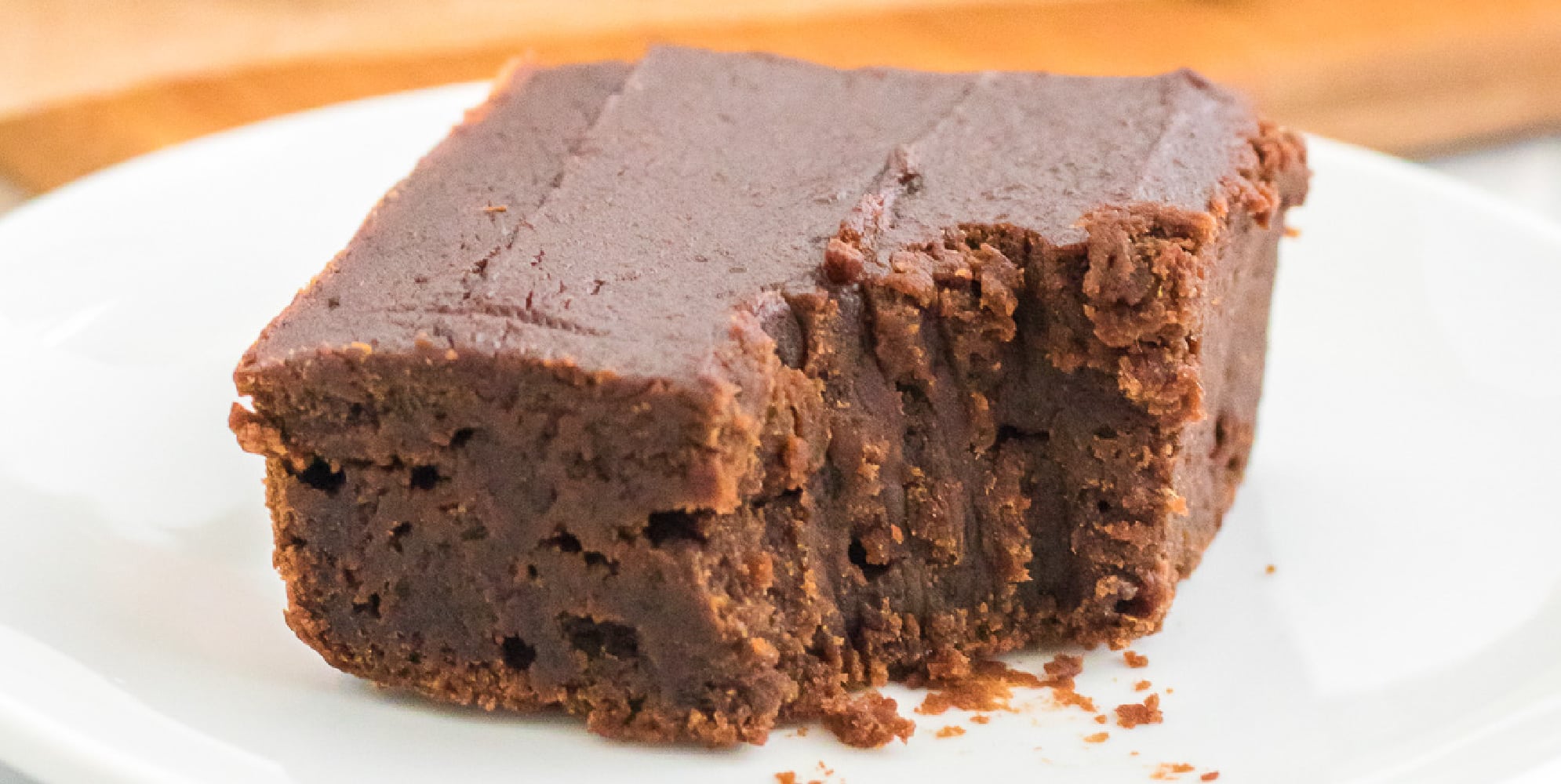 A piece of chocolate pumpkin brownie close up missing a bite on a white plate.