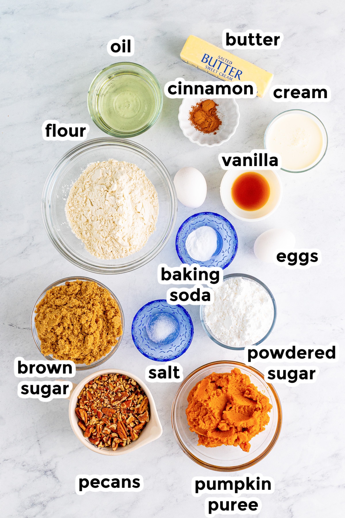 Pumpkin cake ingredients on a table in bowls with text labels.