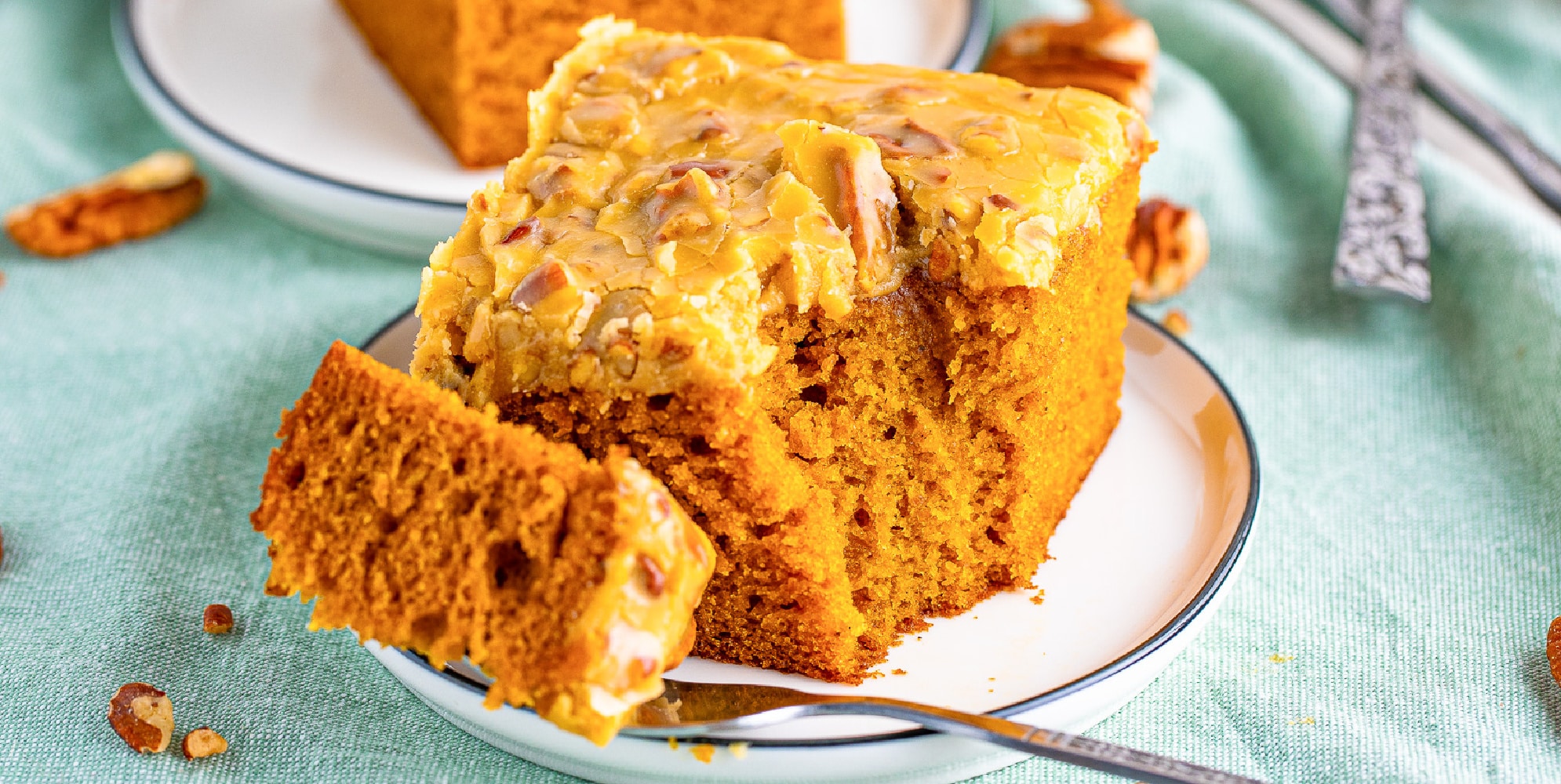 A wide view of a slice of pumpkin cake on a plate with a fork.