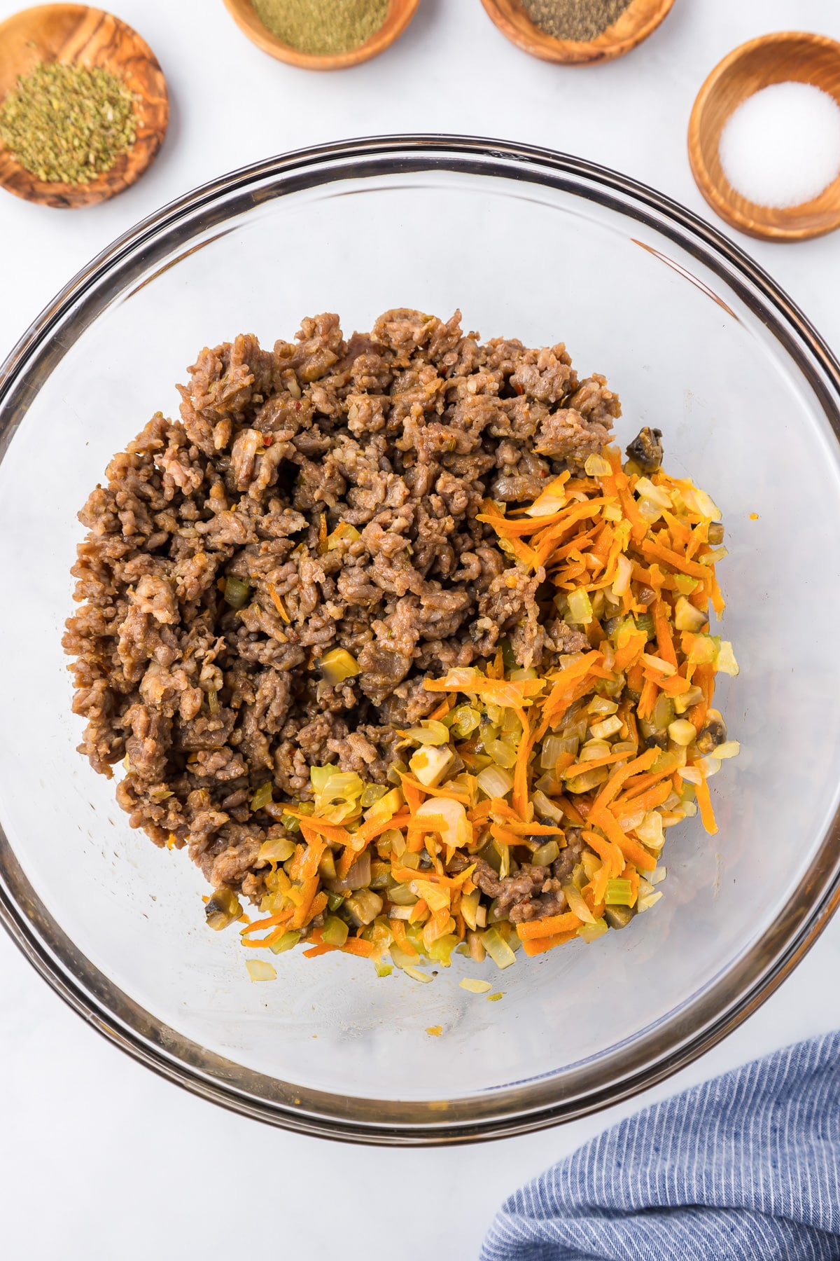 Ground beef, carrots and spices in a large bowl before mixing.