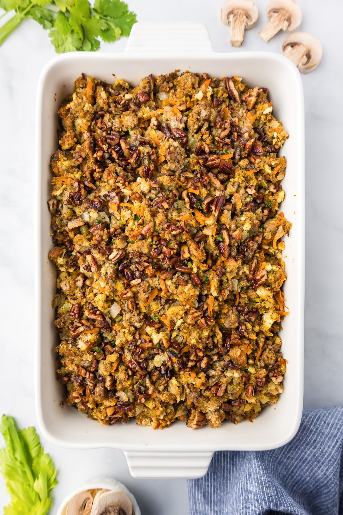 A rectangle baking dish with stuffing topped with pecans.