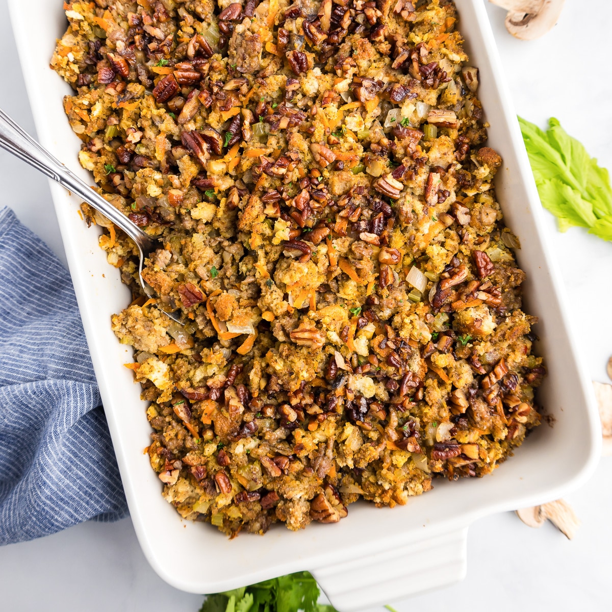 A square view of a rectangular casserole dish with a spoonful of stuffing being scooped from it.