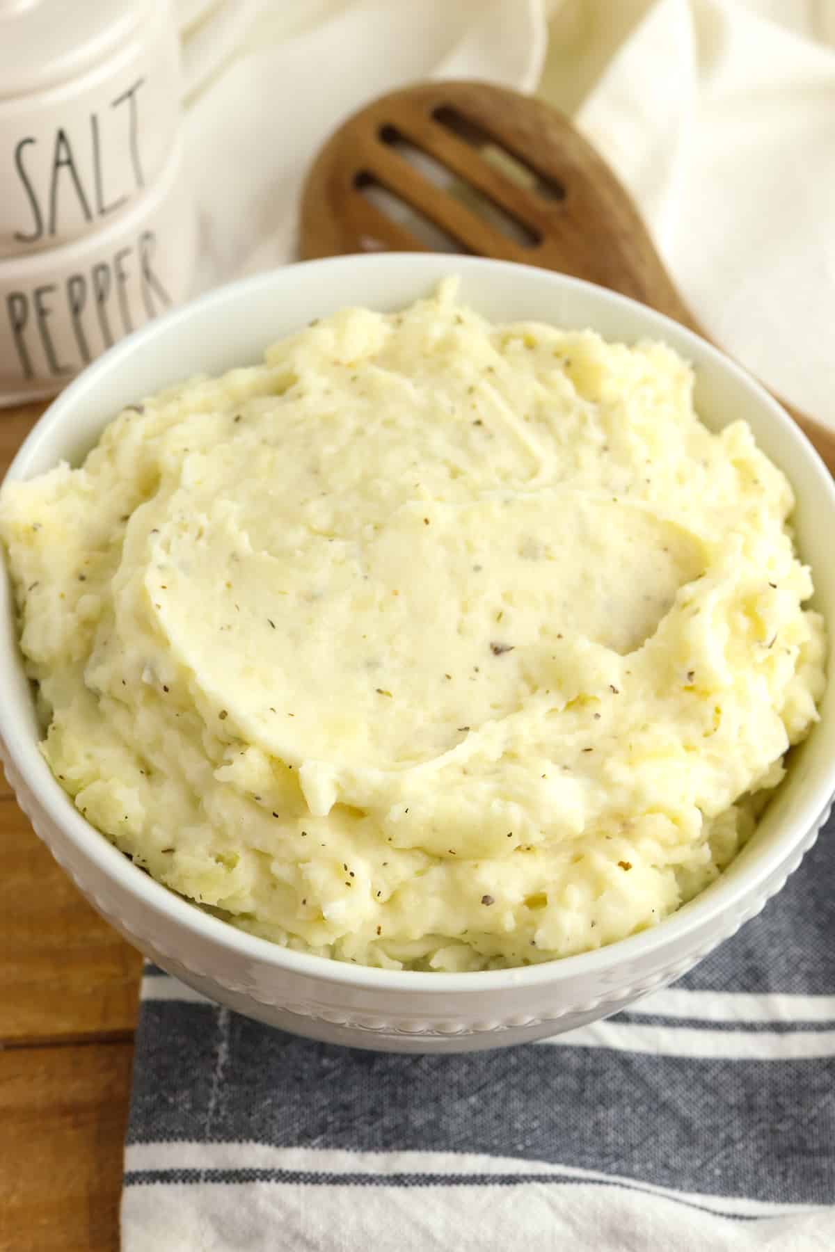 A serving bowl of garlic cream cheesed mashed potatoes on a table.