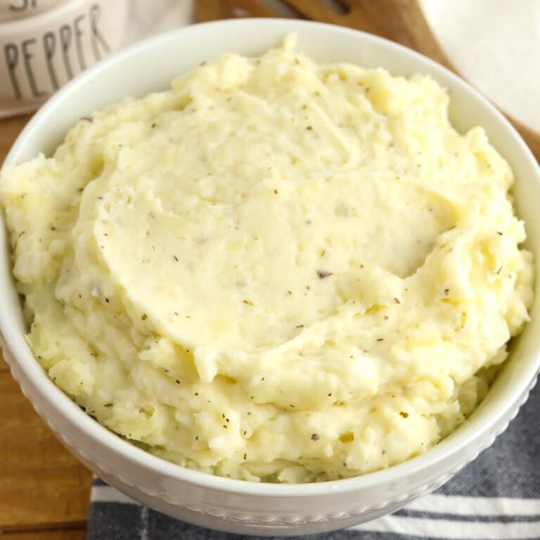 A close up view of a bowl of herb garlic cream mashed potatoes.