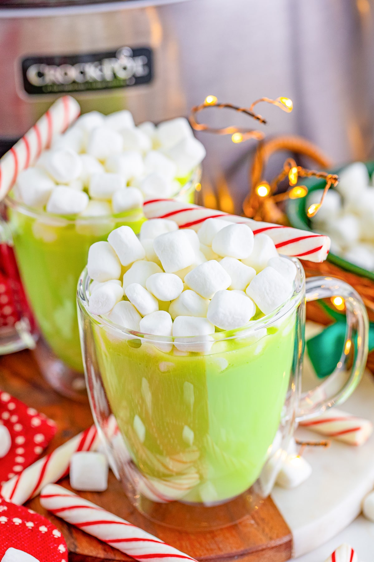 A cup of green Grinch hot chocolate with marshmallows and candy canes on top.