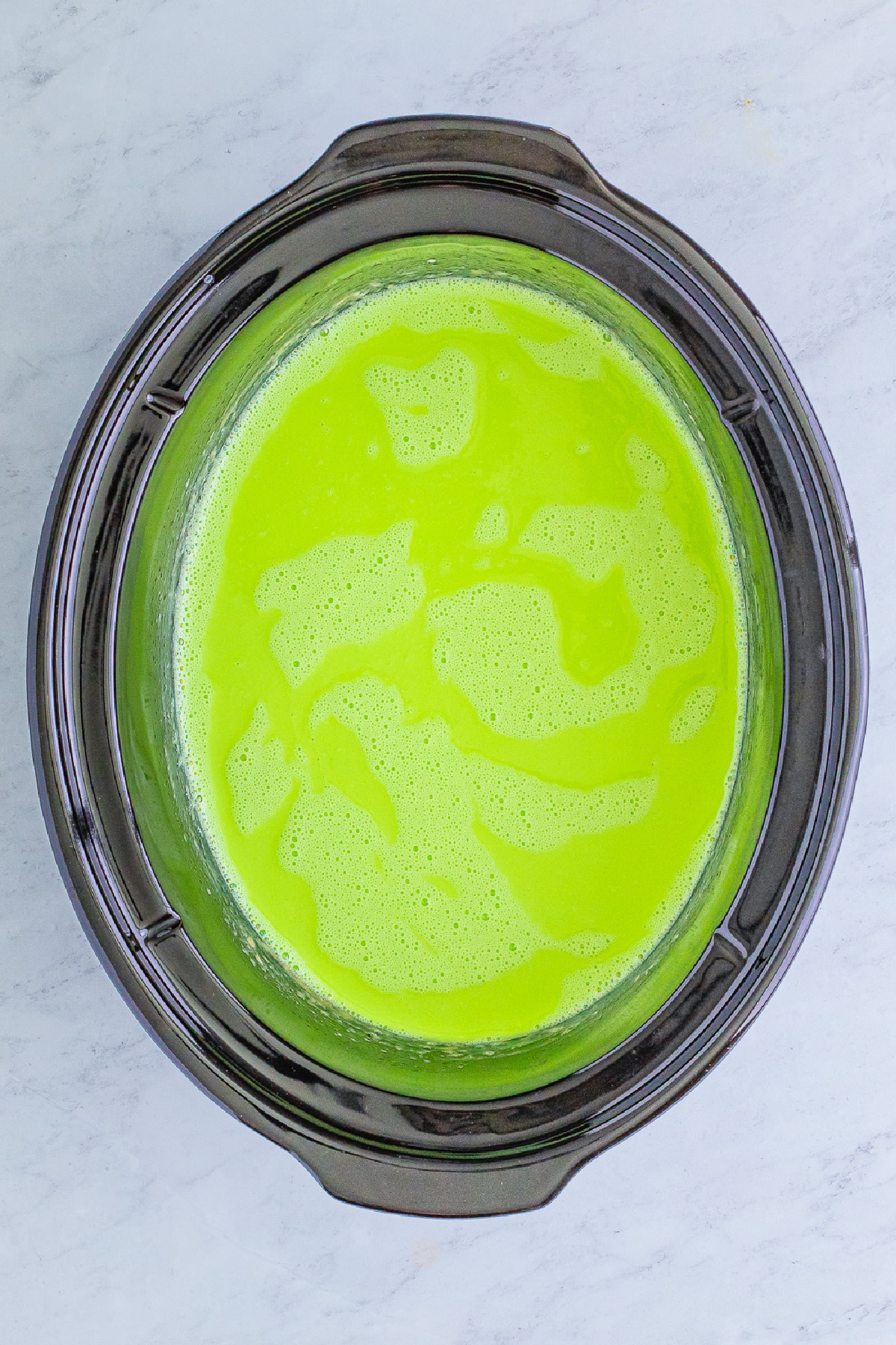 Green colored hot chocolate in a slow cooker from above.